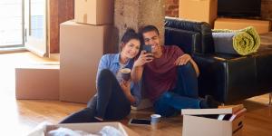 Woman and man smiling and sitting on the floor among packing boxes. Sandy Spring Insurance.