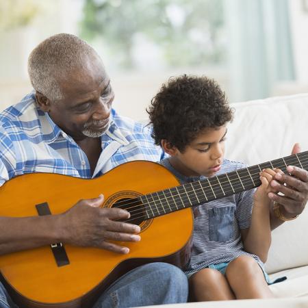 Grandfather teaching grandson the guitar. Sandy Spring Bank Senior Interest Banking.